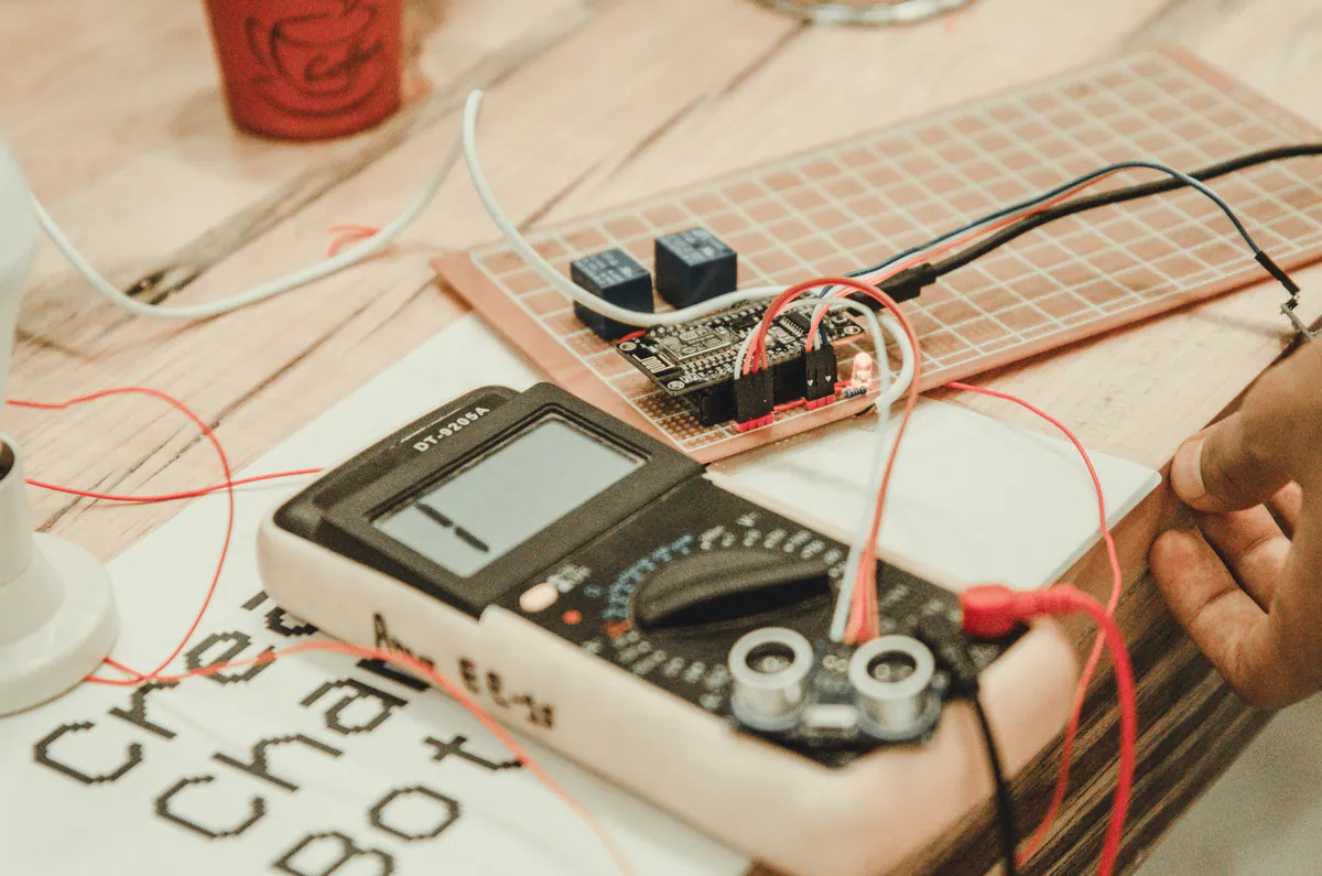 Technician testing an electronic circuit on a breadboard with a digital multimeter.