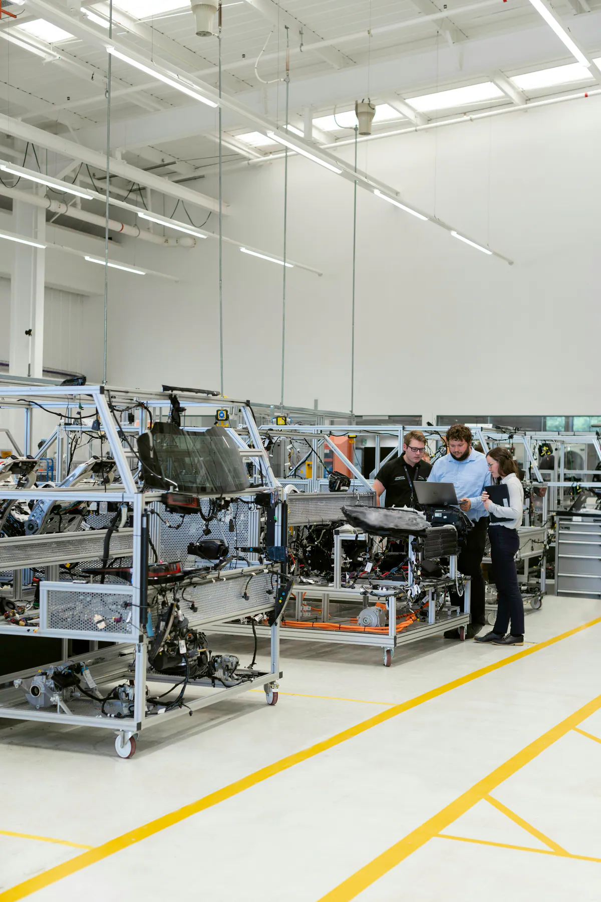 Three engineers inspecting equipment on an automotive manufacturing line.