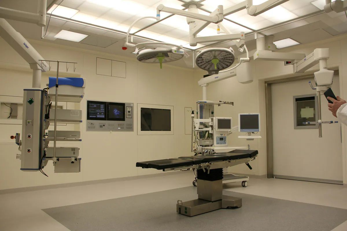 Modern hybrid operating theatre with a surgical table, ceiling lights and imaging equipment.